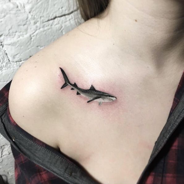 a black and white photo of a woman's shoulder with a shark tattoo on it