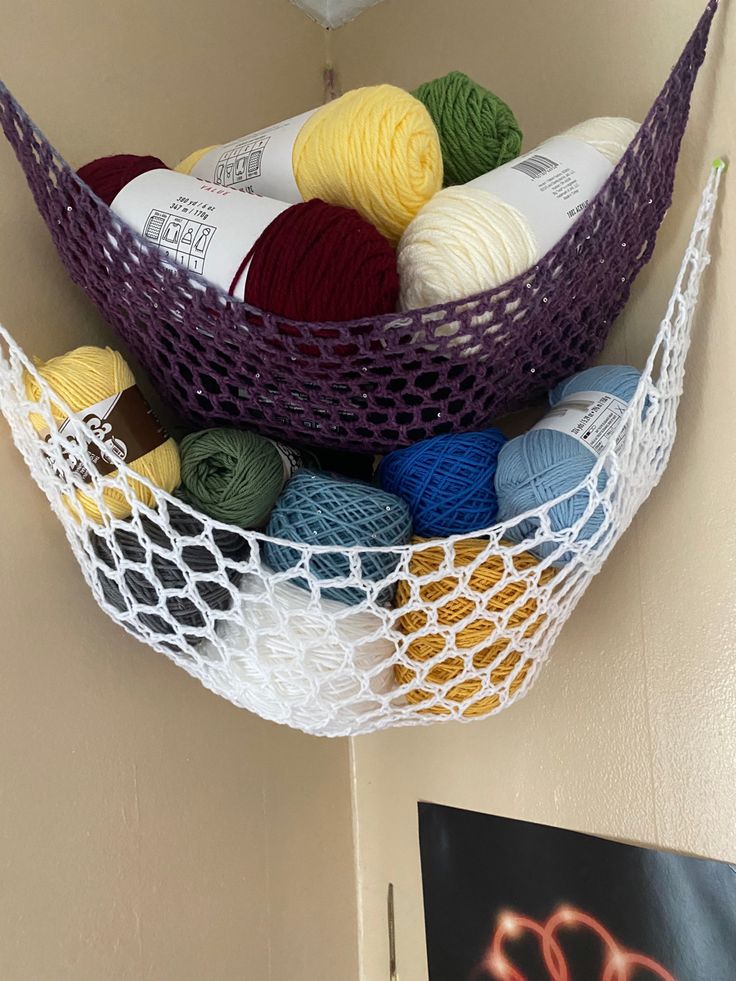 balls of yarn are in a net hanging from the wall