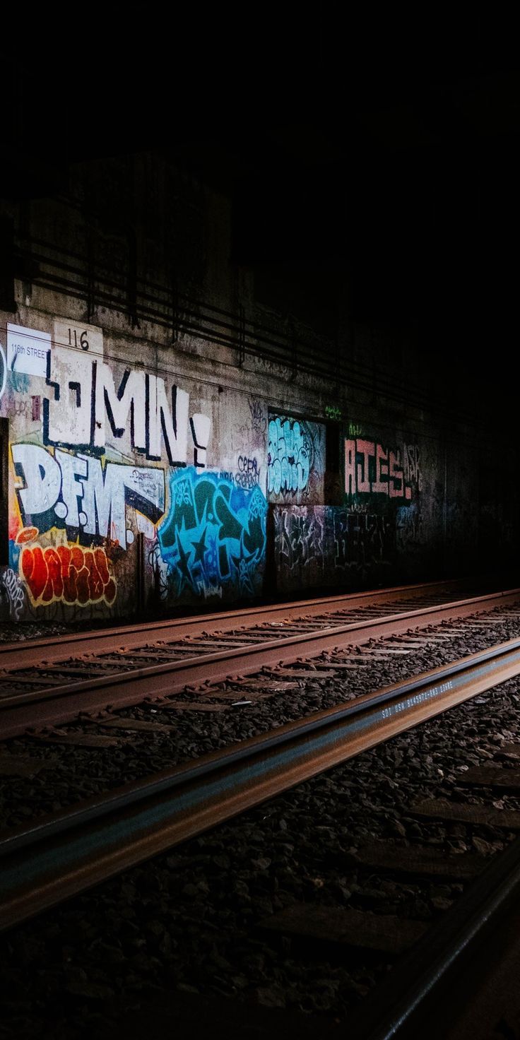 a train track with graffiti on it at night