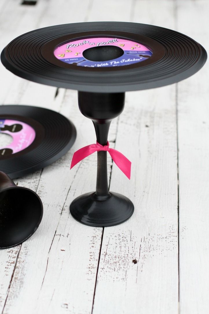 an old record cake stand is decorated with pink ribbon and black plates are on the table