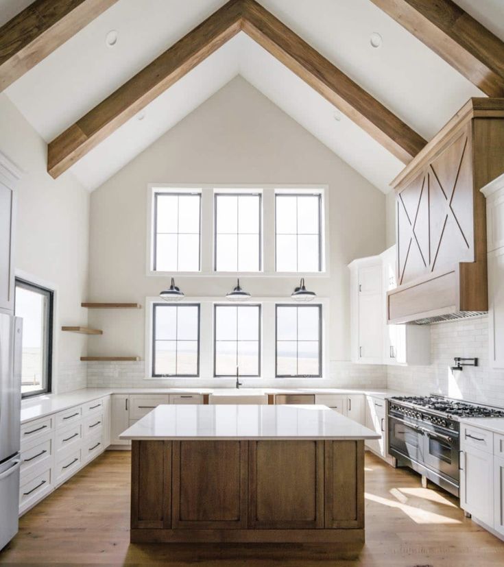 a large kitchen with an island in the middle and wooden beams on the ceiling above it