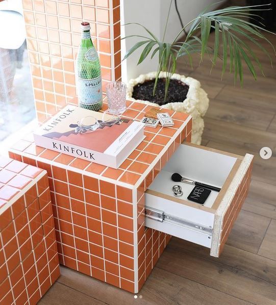 an orange tiled side table with a wine bottle on top and a plant in the middle