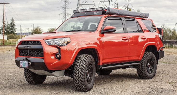 an orange toyota 4runner is parked in the dirt