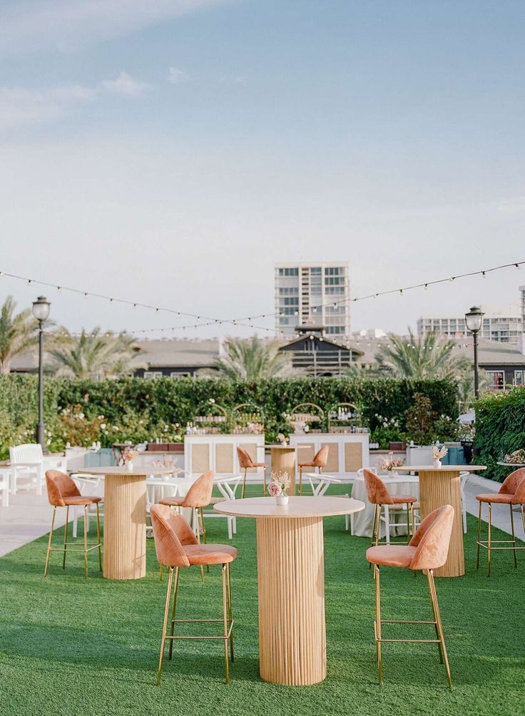 tables and chairs are set up on the grass in front of an outdoor dining area