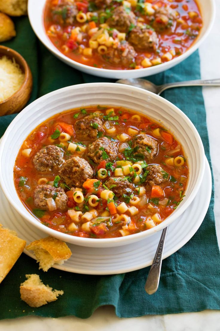 two bowls of meatball soup with bread on the side