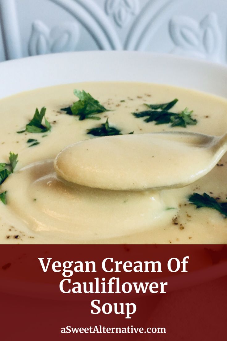 a spoon full of cream of cauliflower soup with parsley on top and the words vegan cream of cauliflower soup above it