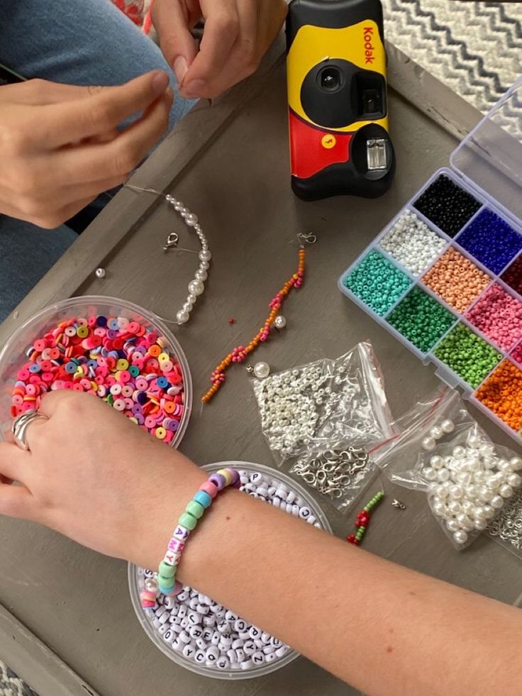 a person sitting at a table with beads and other crafting supplies on the table