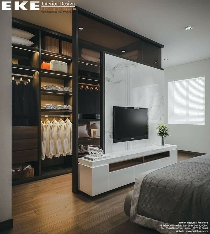 an image of a bedroom setting with clothes on the rack and tv in the closet