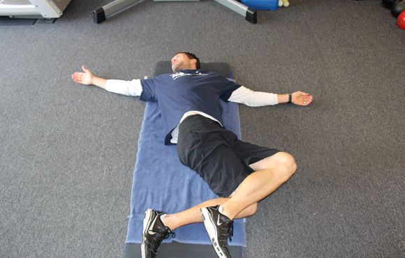 a man laying on top of a blue mat in a gym