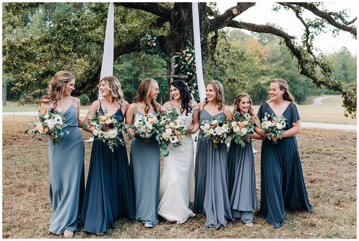 a group of women standing next to each other in front of a tree with flowers