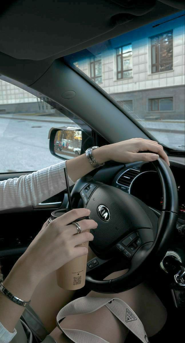 the woman is driving her car and drinking coffee