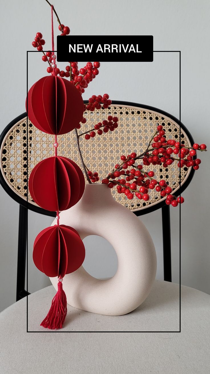 a white vase with red flowers hanging from it's sides on a black chair