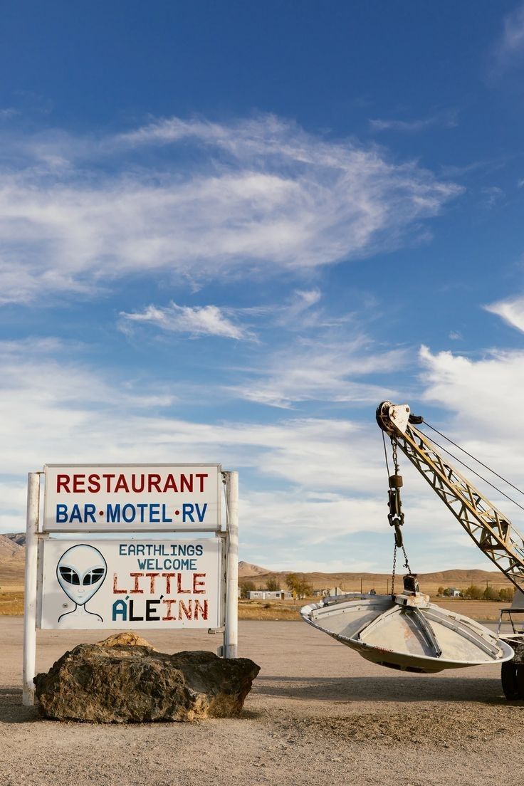 a sign that says restaurant bar motel rv next to a large crane in the desert