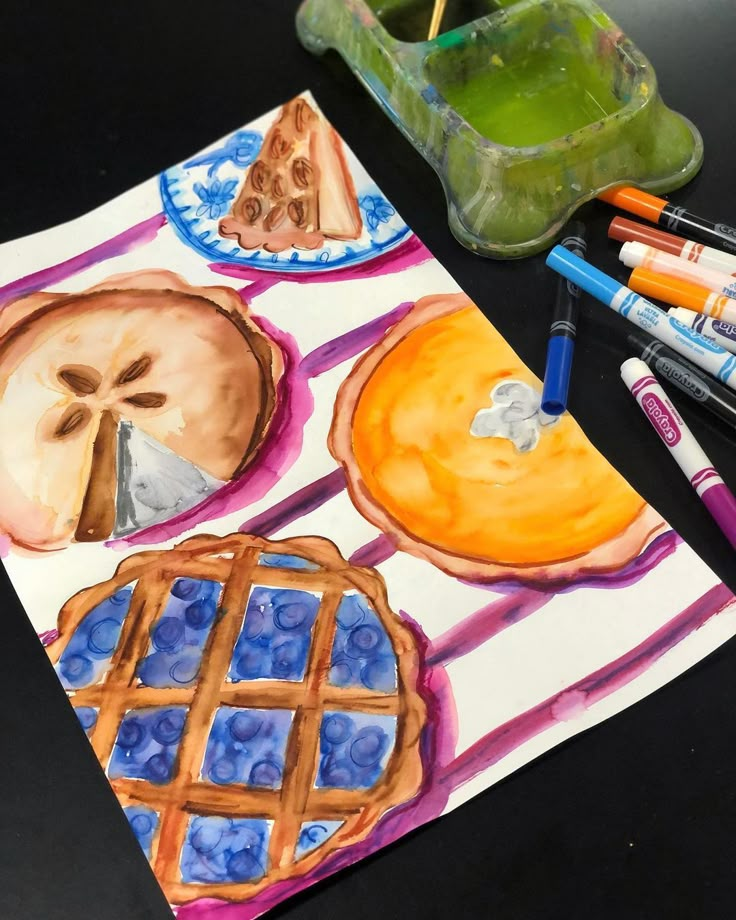 an art project with watercolors and crayons on the table next to it