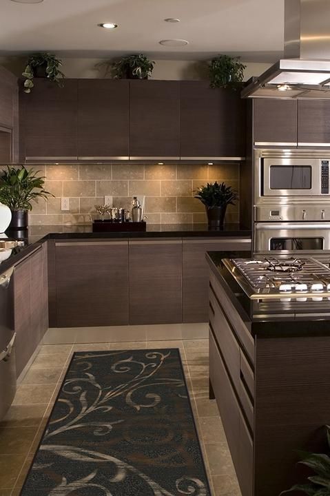 a modern kitchen with stainless steel appliances and wood cabinets, along with an area rug