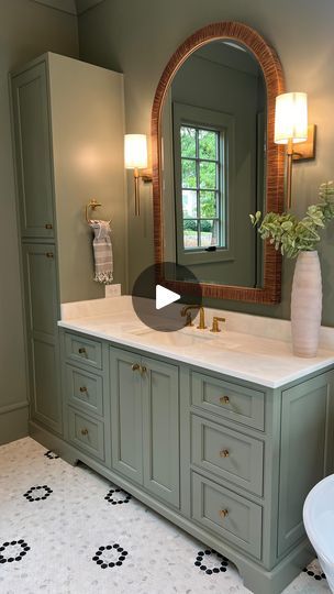 a bathroom with green cabinets and a large mirror on the wall above the sink, along with a white toilet