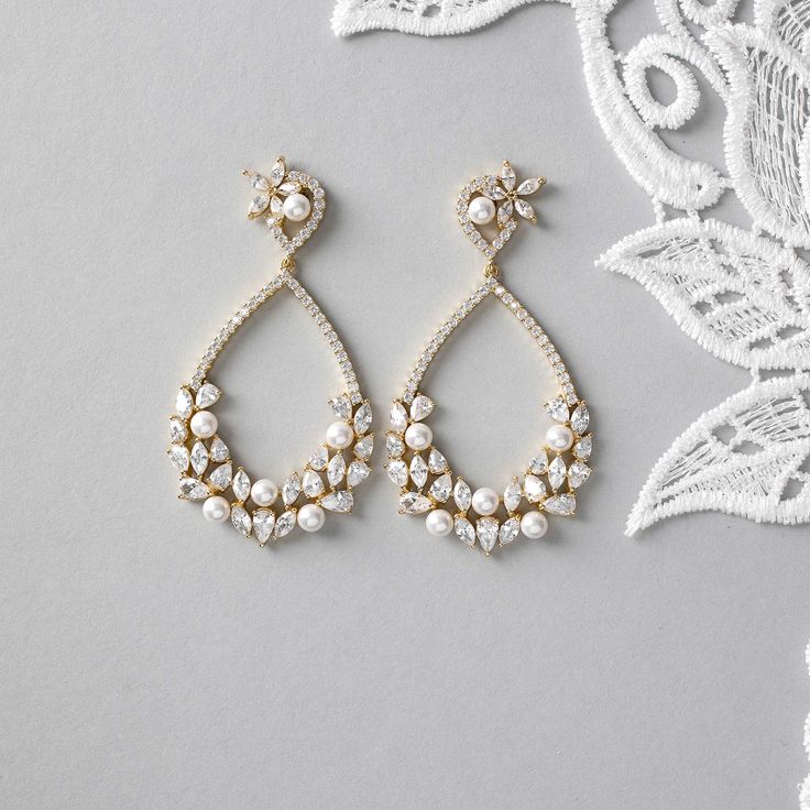 These earrings feature a teardrop-shaped hoop adorned with a charming cluster of pearls, pear, and marquise cut CZ jewels on the lower half. Boasting a length of 2.25 inches, these earrings have titanium post backs and are crafted from rhodium or gold plated brass with AAA CZ stones. Plus, they are lead, nickel, and cadmium free for a worry-free and luxurious accessory. Rustic Wedding Earrings, Teardrop Bridal Earrings, Silver Bridal Earrings, 2025 Wedding, Black And White Earrings, Weaving Ideas, Bride Accessories, Jewellery Ideas, Hot Nails