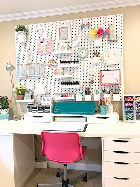 a white desk topped with a pink chair next to a wall covered in pictures and photos