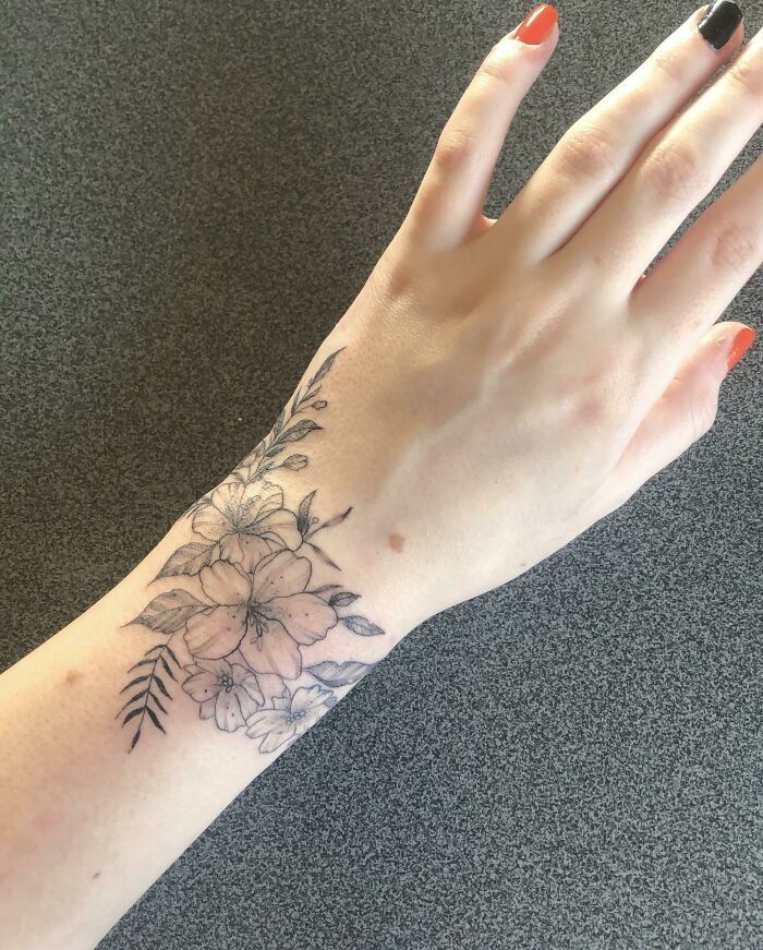 a woman's hand with a flower tattoo on it