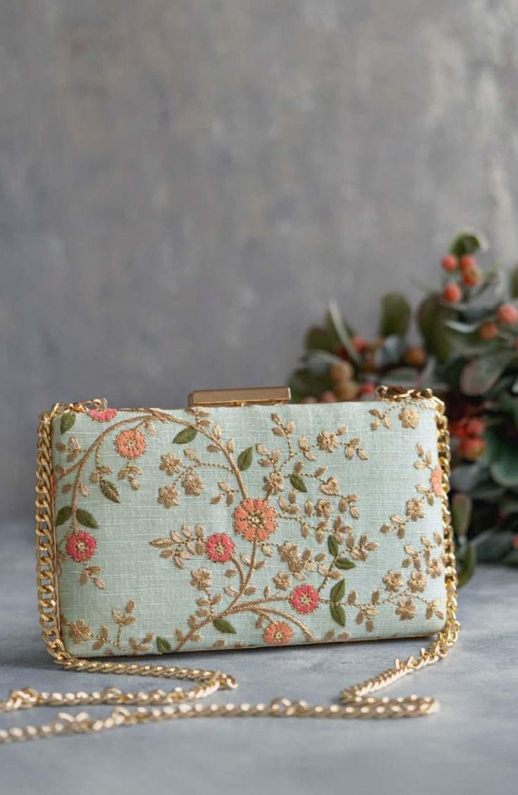 Our Floral creeper clutches are super-hot, year-round! The traditional silhouette with exquisite floral embroidery and the metal chain sling are perfect to add that oomph to your overall look and make a strong style statement, no matter what the occasion. Embroidered front and back. Dimensions (LxB): 8"x4.5" (20 cm x 11 cm) Handle length: 47" (120 cm) Handle drop: 23" (58 cm) Material: Embroidered poly silk, poly satin lining, gold metal clutch frame, gold metal sling. Features: metal lock closu