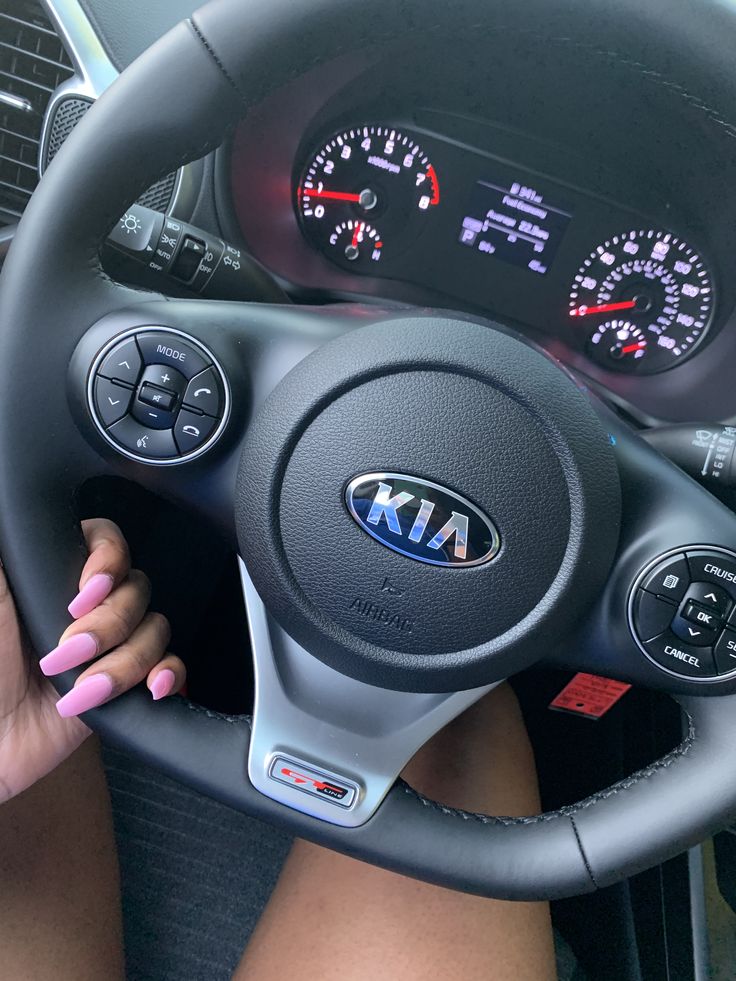 a woman sitting in the drivers seat of a car with her hands on the steering wheel