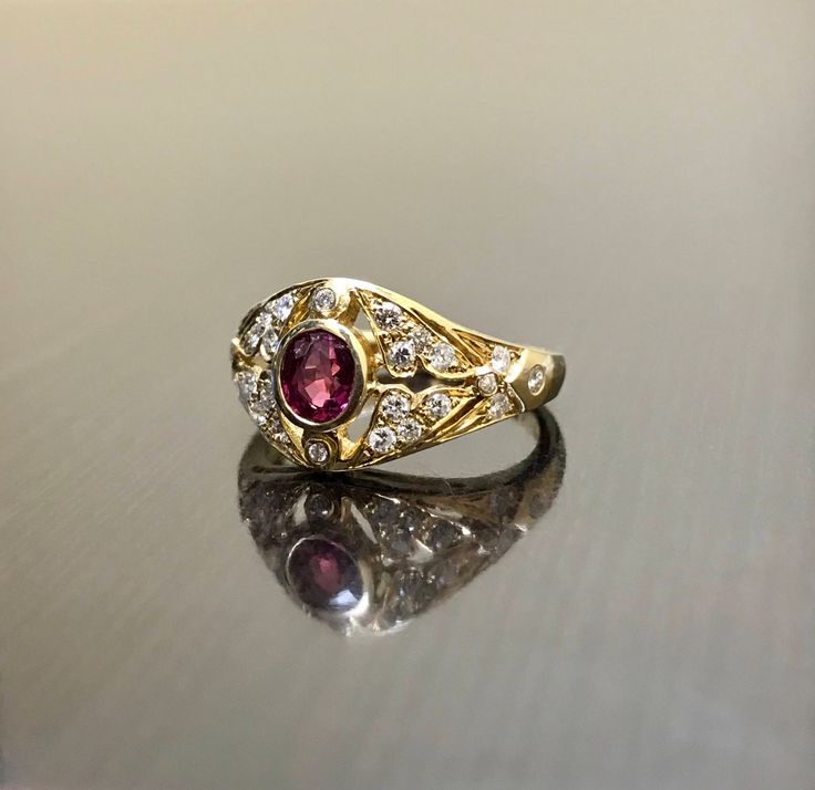 DeKara Designs Collection Metal- 18K Yellow Gold, .750. Stones- 1 Oval Ruby 0.50, 28 Round Diamonds G Color VS2 Clarity 0.22 Carats. Art Deco 18K Yellow Gold Ruby Diamond Engagement Ring. This ring features a beautiful reddish pink ruby that is half carat total weight, surrounded by 28 round diamonds. The center ruby is bezel set, 20 pave set diamonds, and 8 bezel set diamonds. The ring is entirely handmade, and could be hand engraved for an additional $200.00. The ring is a size 6 1/2, and coul Formal Oval Ruby Ring With Single Cut Diamonds, Traditional Oval Ruby Ring For Anniversary, Exquisite Yellow Gold Ruby Wedding Ring, Exquisite Yellow Gold Ruby Ring For Wedding, Yellow Gold Hallmarked Ruby Ring For Wedding, Hallmarked Yellow Gold Ruby Ring For Wedding, 22k Yellow Gold Ruby Wedding Ring, Yellow Gold 22k Ruby Wedding Ring, Oval Yellow Gold Ruby Ring For Ceremonial Occasions