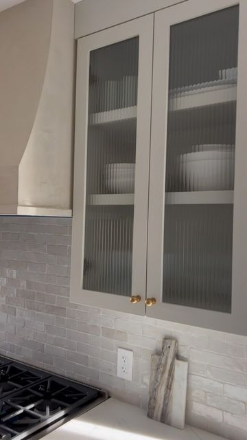 a kitchen with white cabinets and silver counter tops in front of a stove top oven