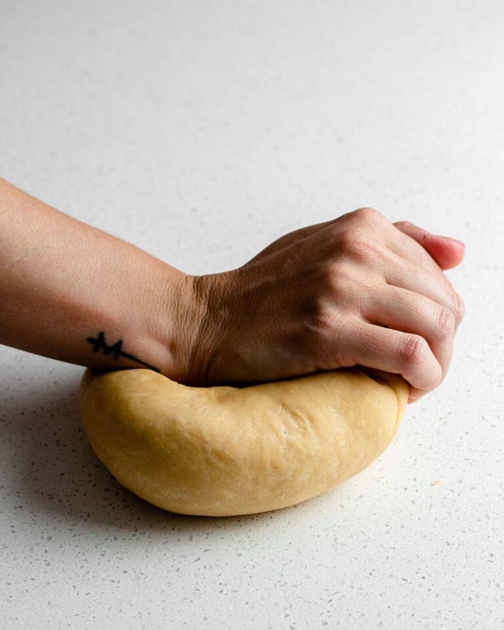 a person's hand resting on top of a piece of bread that has been kneaded together