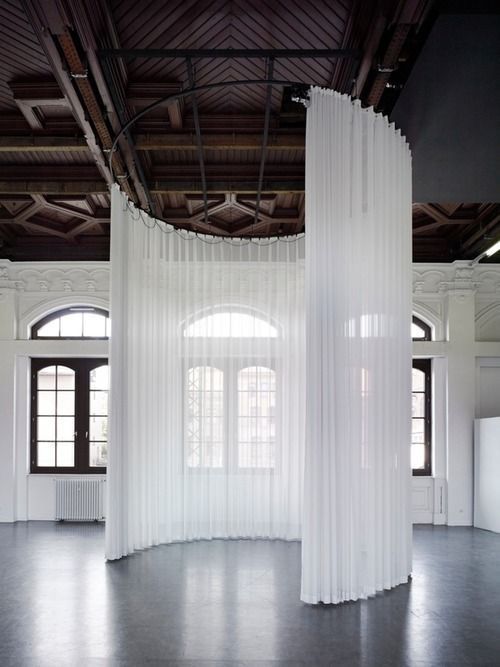 an empty room with white curtains hanging from the ceiling