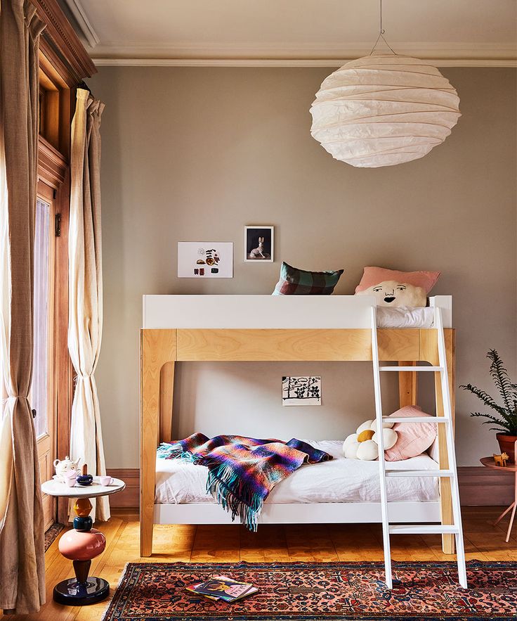 a bedroom with a bunk bed, rug and hanging lamp in the corner on the wall