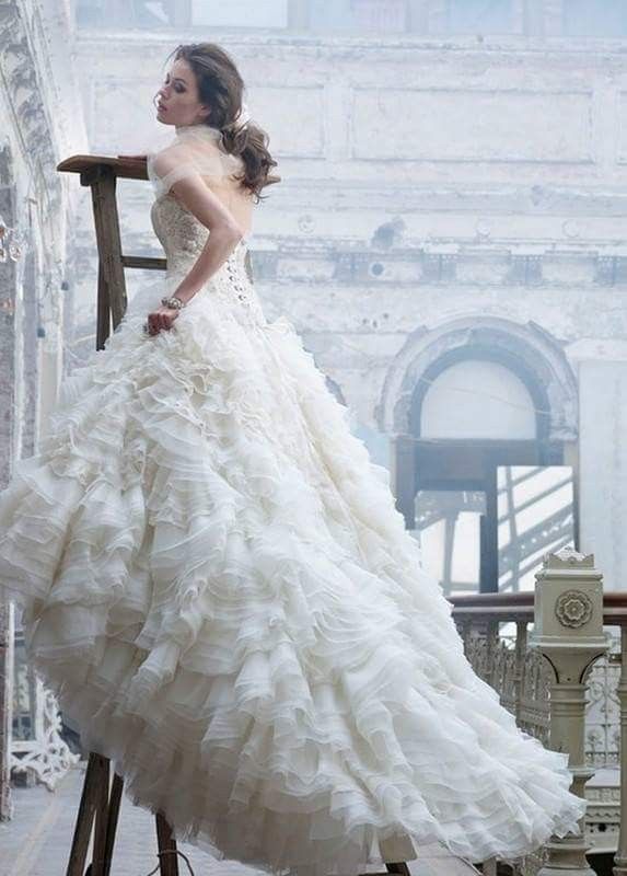 a woman in a wedding dress leaning on a chair