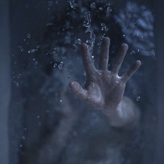 a hand reaching out from the water in front of a window with it's reflection