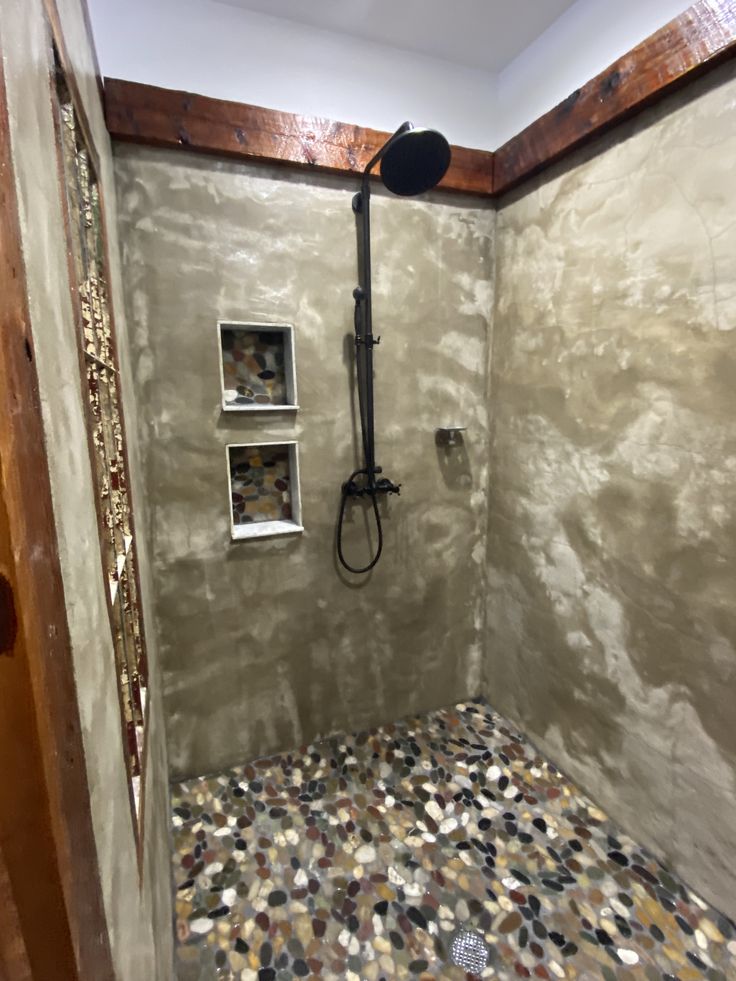 a bathroom with a shower head and mosaic tile on the floor in front of it