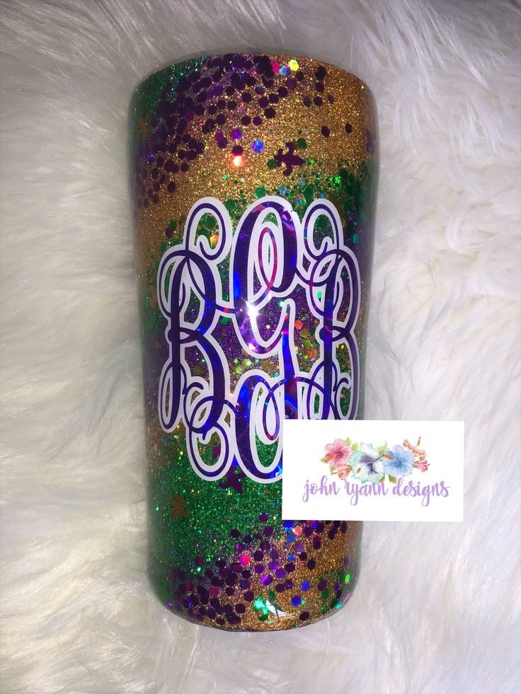 the monogrammed tumbler has been decorated with purple, green and gold glitters