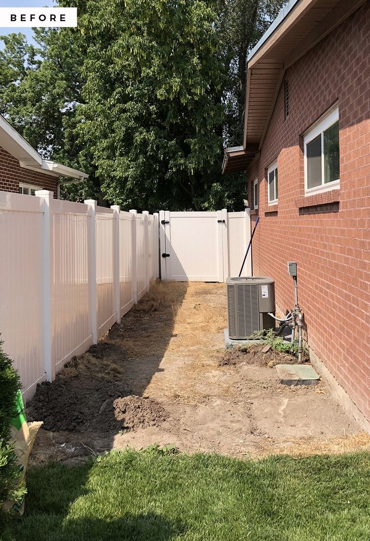 a white fence next to a red brick house