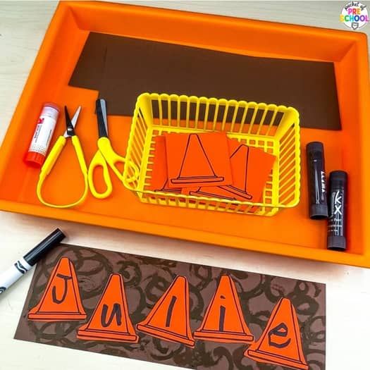 an orange tray with construction signs and markers on it next to scissors, marker pens and glue