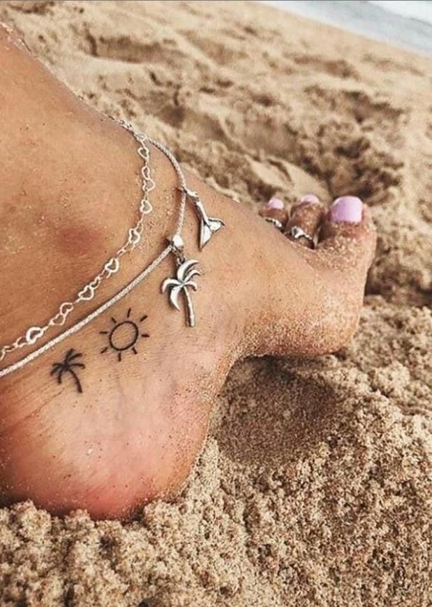 a woman's foot with tattoos on the beach