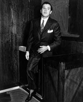 a man in a suit and tie leaning on a table