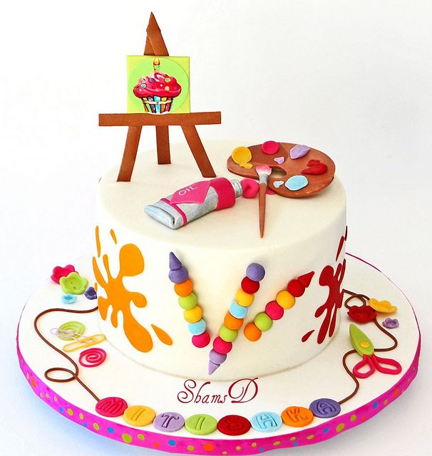 a birthday cake decorated with an artist's palette and crayons on it