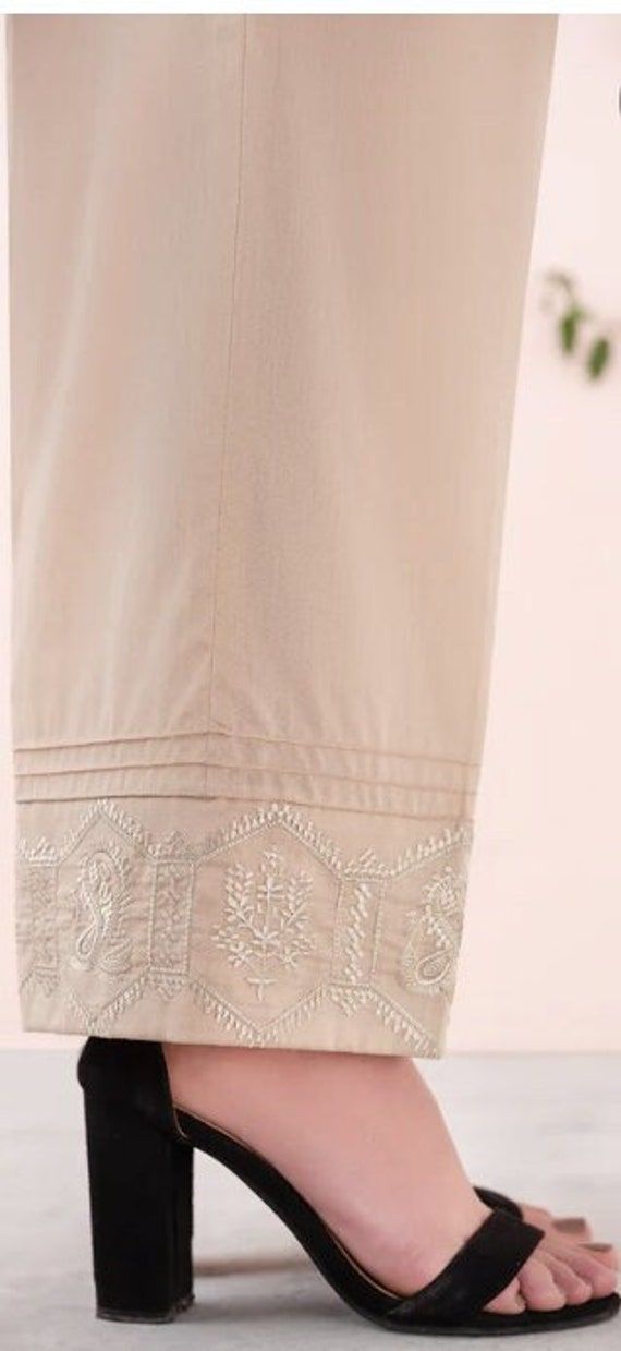 Look your best by wearing this embroidered trousers to pair with any dress. Detail: - Color: Gold - Fabric: Cambric - Loose Straight Trousers with Pintucks - Embroidered Hem Elegant Embroidered Summer Pants, Embroidered Bottoms For Summer Wedding, Summer Cotton Bottoms With Lace Work, Embroidered Summer Wedding Bottoms, Summer Wedding Embroidered Bottoms, Elegant Chikankari Embroidered Bottoms For Summer, Eid Cotton Bottoms With Embroidered Border, Elegant Summer Bottoms With Chikankari Embroidery, Elegant Straight Pants With Embroidered Border