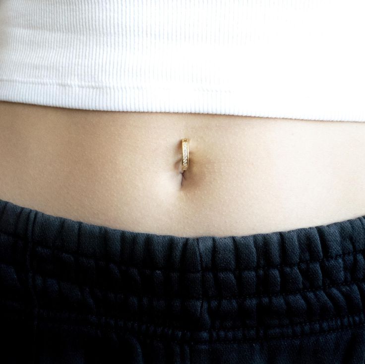 a woman's stomach with a tiny gold ring on the middle of her belly