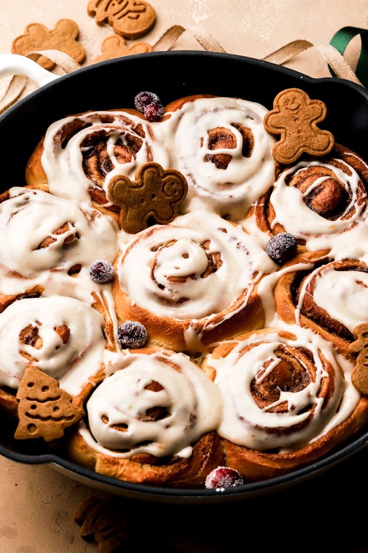 a pan filled with cinnamon rolls covered in icing and pretzel shaped cookies