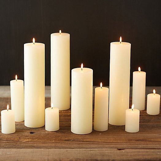 many white candles are lined up on a wooden table