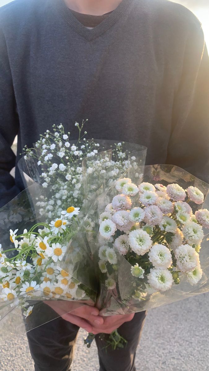 a man holding a bunch of flowers in his hands with the sun shining on him