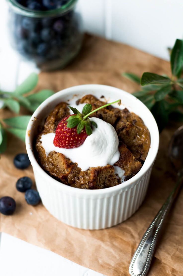 a white bowl filled with fruit and topped with whipped cream