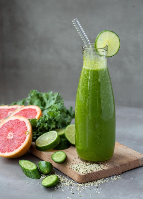 a green smoothie in a glass next to sliced grapefruit