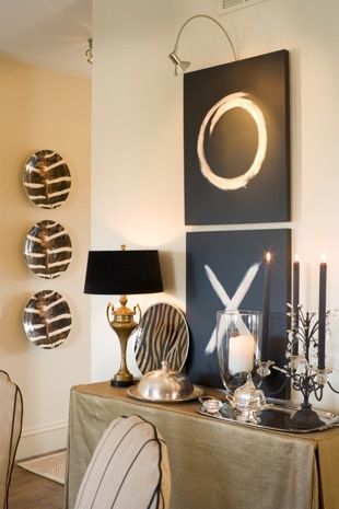 a living room filled with furniture and art on the wall next to a table topped with candles