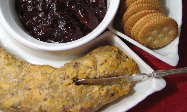 a white plate topped with food next to crackers and fruit jelly in a bowl