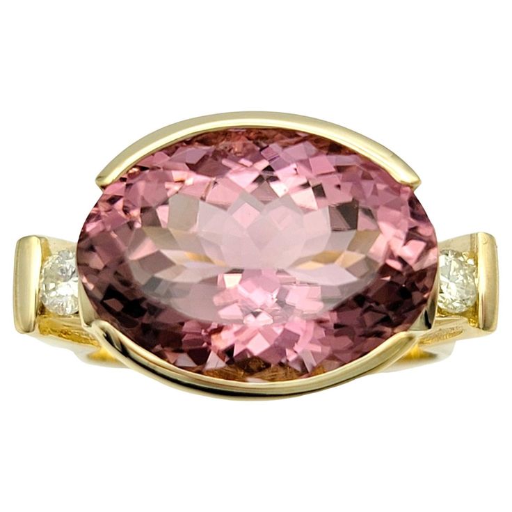 Ring Size: 6.75 This exquisite oval pink tourmaline cocktail ring, set in 14 karat yellow gold, is a stunning ring that features a distinctive east-west setting. The vibrant oval pink tourmaline at the center is flanked by sparkling diamonds on each side, adding a touch of brilliance and elegance. The band of the ring boasts a unique squared shape, offering a modern twist to this classic design. Perfect for special occasions or as a statement piece, this ring combines luxurious materials with di Diamond Cocktail Ring, Diamond Cocktail Rings, Oval Rings, Fine Jewelry Collection, East West, Pink Diamond, Sparkle Diamonds, Cocktail Ring, Diamond Clarity