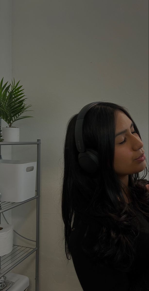 a woman with headphones standing in front of a mirror